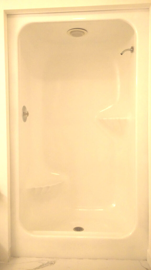 Shiny white enclosed shower after refinishing